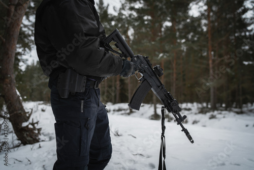 An AK 12 rifle in the hands of a military man in the forest in winter.