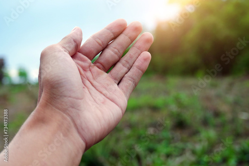 Man's hand touches warm sunlight through fingertips. Hand ready. Freedom in nature, and spirituality concept. © Ka Iki