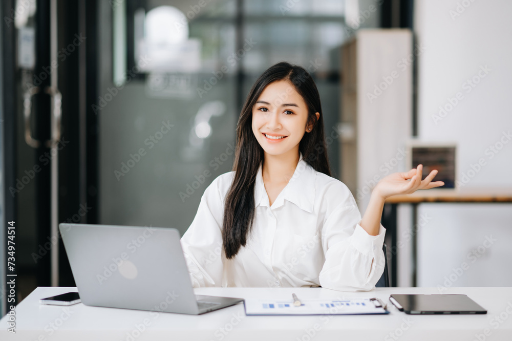 Asian businesswoman working with working notepad, tablet and laptop documents talking on the tablet and laptop Asian businesswoman working with working notepad, tablet and laptop documents talking on the tablet and laptop