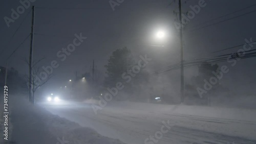 Car traffic on a winter road during a heavy snow storm with gusty winds at night in Dartmouth, Canada , 2023. Ice on the road and poor visibility during snowfall on the road with cars. photo