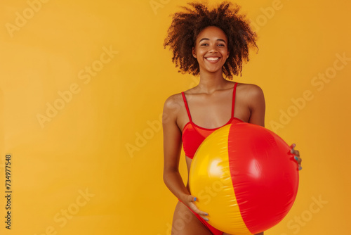 Funny young happy African American woman in red swimsuit having fun holding inflatable ball and going on summer holiday trip standing on yellow studio background. Vacation tour and travel concept. © AI_images