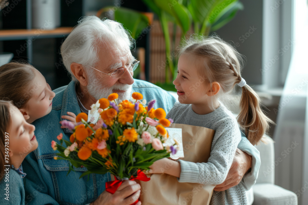 Happy senior man receives presents from his grandchildren. Children make their grandfather a birthday surprise. Little kids give their grandpa a gift card and a bouquet of flowers Happy senior man receives presents from his grandchildren. Children make their grandfather a birthday surprise. Little kids give their grandpa a gift card and a bouquet of flowers