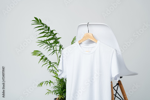 White blank t-shirt hanging on chair in empty room