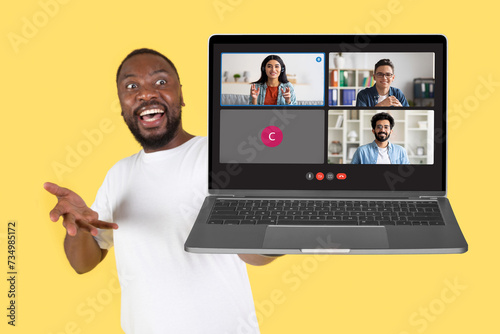 Canvas Print An exuberant man joyously gestures towards a laptop displaying a video conferenc