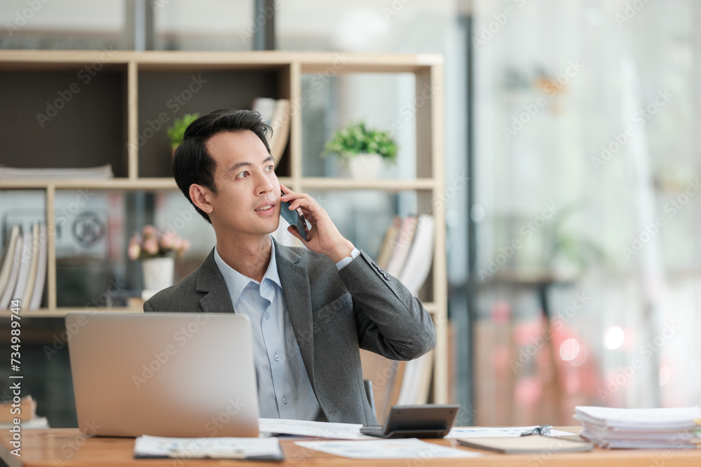 Happy asian business man have the joy of talking on the smartphone, tablet and laptop in the home office Happy asian business man have the joy of talking on the smartphone, tablet and laptop in the home office