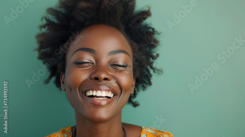Portrait of delightful, smiling African-American woman with brunette curly hair against light mint background.