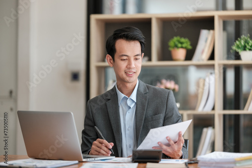 Young Businessman Using Laptop Computer in Modern Office. Manager Thinks About Successful Financial Ideas. Happy Man Smiling About Finding Problem Solving Solutions for Company.