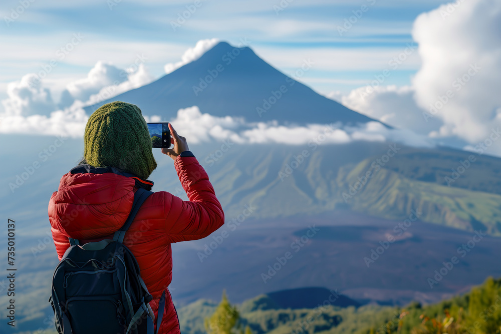 Person in Red Jacket Capturing Volcano View with Smartphone
