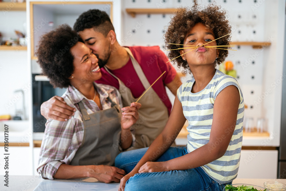Overjoyed young african american family with kid have fun cooking at home together,