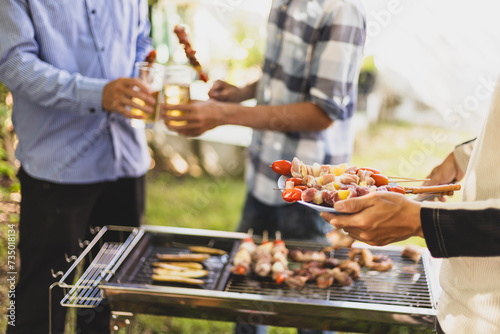 Group of friends grilling delicious barbecued meat on the grill at a house party.