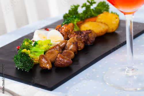 Appetizing braised chicken hearts with vegetable garnish of baked potatoes, broccoli, carrots and quail eggs