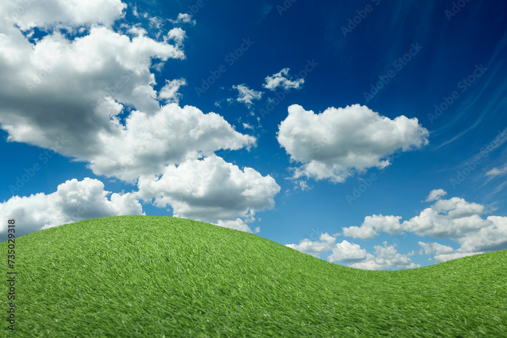 Lush green grass under blue sky with fluffy clouds