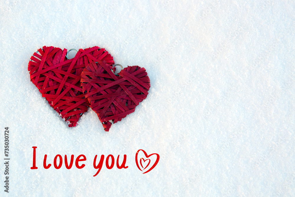 Valentines day background with i love you text and two red hearts on white snow .