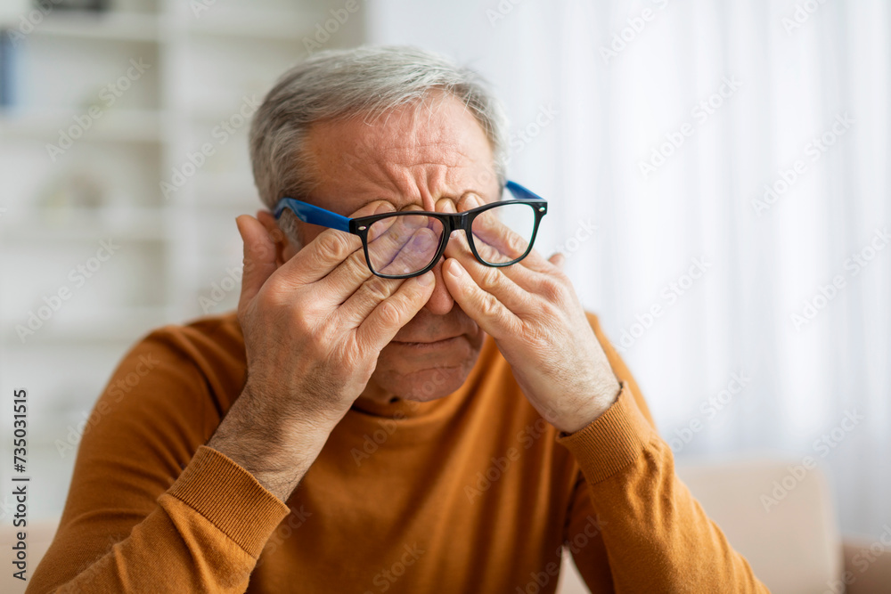 Tired eldery man rubbing eyes, home interior Tired eldery man rubbing eyes, home interior