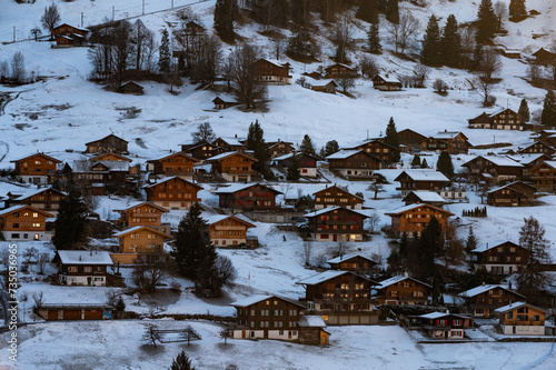 Grindelwald villages with wooden chalets covered with snow in cold winter season at the blue hours in Swiss Alps
