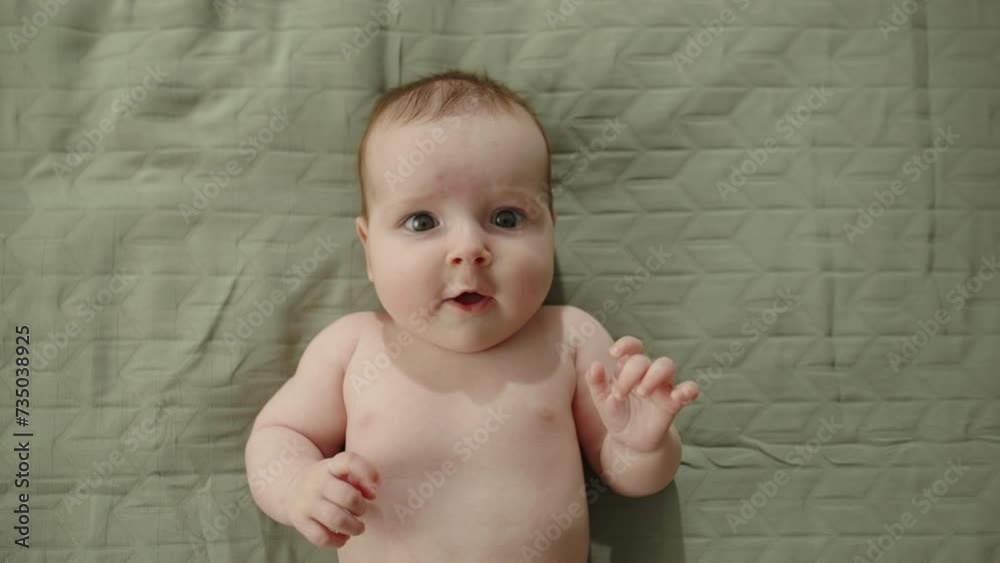 Vidéo Stock Child lying on bed top view. Green sheets, naked little