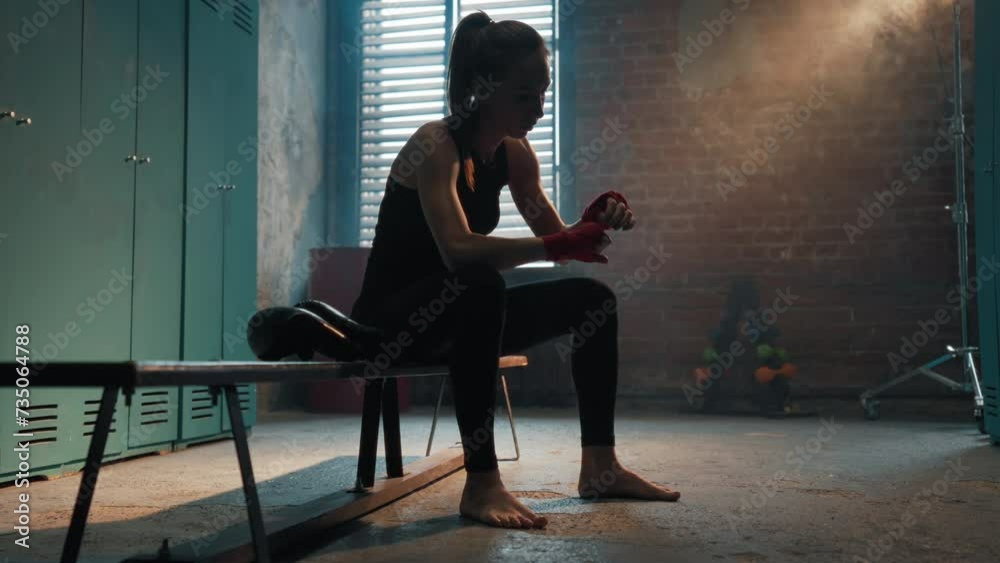 Serious young woman fighter boxer wraps hands wrists with boxing ...