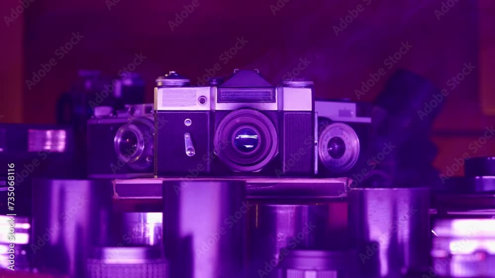 Retro camera with a collection of lenses in neon purple light. Vintage design, vintage lenses. Antiques for photographers. Old technology, hobbies, creativity. Photo art. Close up.