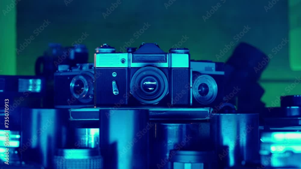 Retro camera with a collection of lenses in neon blue light. Vintage design, vintage lenses. Antiques for photographers. Old technology, hobbies, creativity. Photo art. Close up.