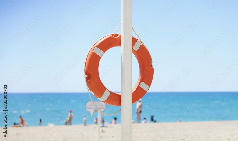A red lifebuoy hangs on the beach, close-up. Water rescue, accident, protective measures, maritime safety