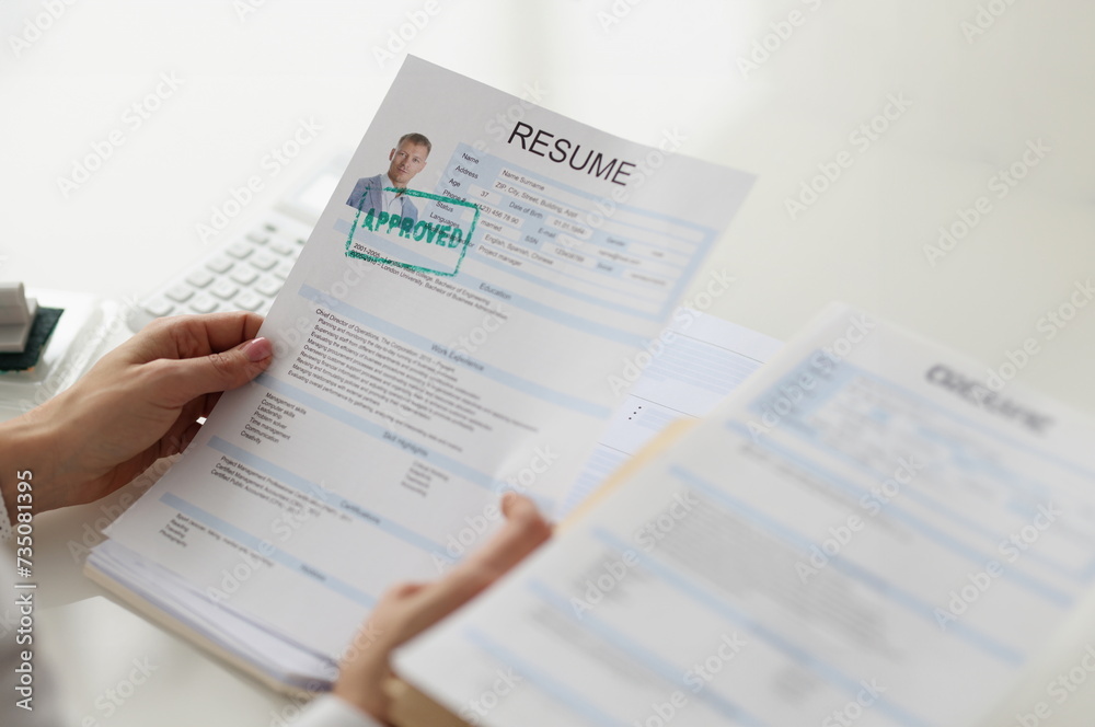 Obraz premium Hands holding a resume of a man, close-up. Job candidate selection. Recruitment agency, vacancy closing