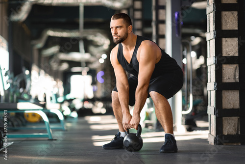 Motivated Muscular Man Training With Kettlebell At Modern Gym Interior 
