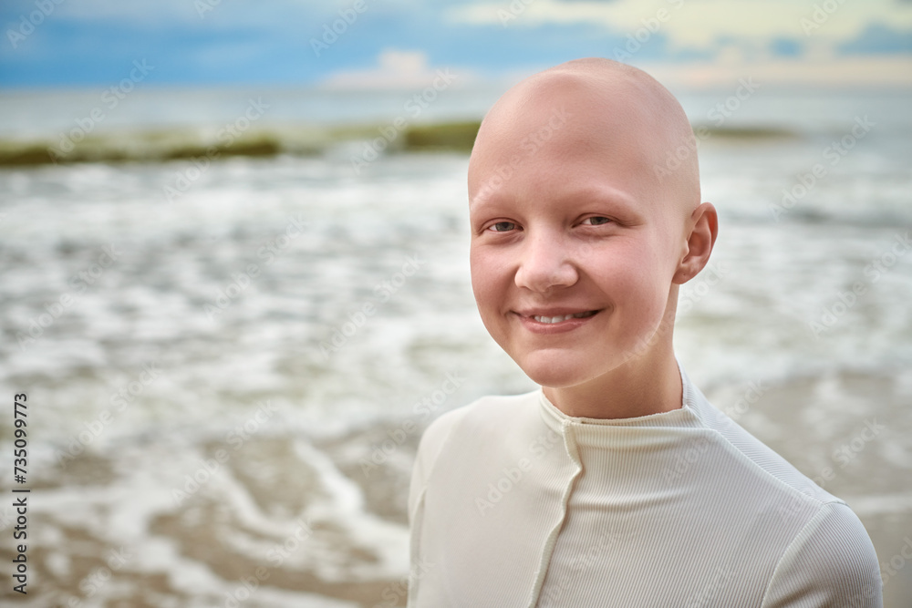 Close up portrait of smiling hairless girl with alopecia in white futuristic costume on sea background, bald pretty teenage girl showcasing unique beauty and identity with pride, unusual alien girl