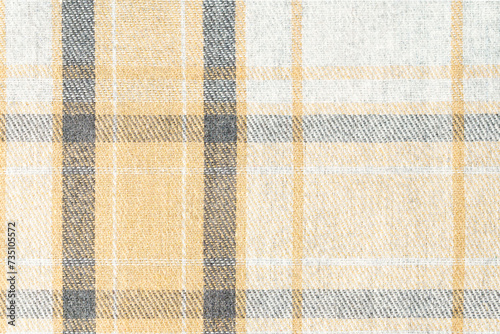 Close-up texture of tartan fabric in beige and gray colors at an angle. Concept of materials and fabrics for clothing and textiles. Background for your design.