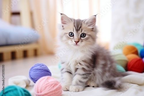 White striped kitten sitting next to a basket ball of yarn in the interior