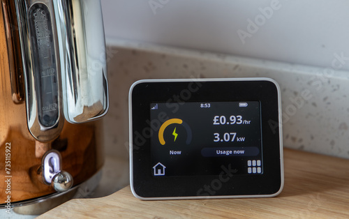 Remote smart meter display showing electricity used in British pounds and kilowatt when kettle switched on.