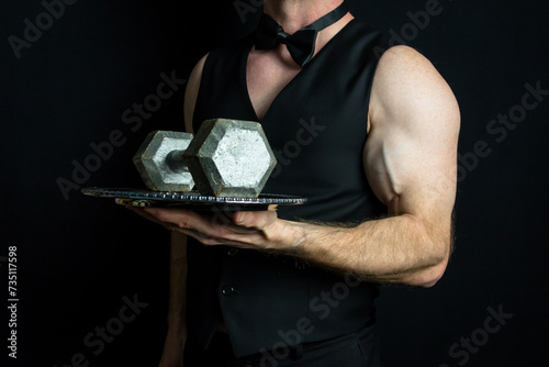 Muscular Waiter in Black Vest and Bare Arms Holding Dumbbell on Serving Tray. Sexy Bodybuilding Butler.