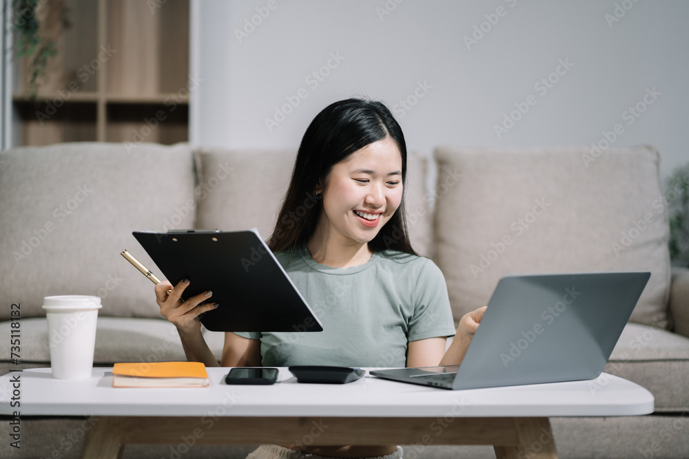 Woman sitting on sofa using mobile phone to calculate household expenses, hand holding account book for income-expense. Woman sitting on sofa using mobile phone to calculate household expenses, hand holding account book for income-expense.