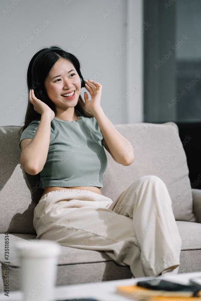 Smiling girl relaxing at home, she is playing music using smartphone tablet, laptop, and wearing headphones. Smiling girl relaxing at home, she is playing music using smartphone tablet, laptop, and wearing headphones.