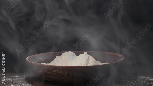Men's hands pour white flour with smoke