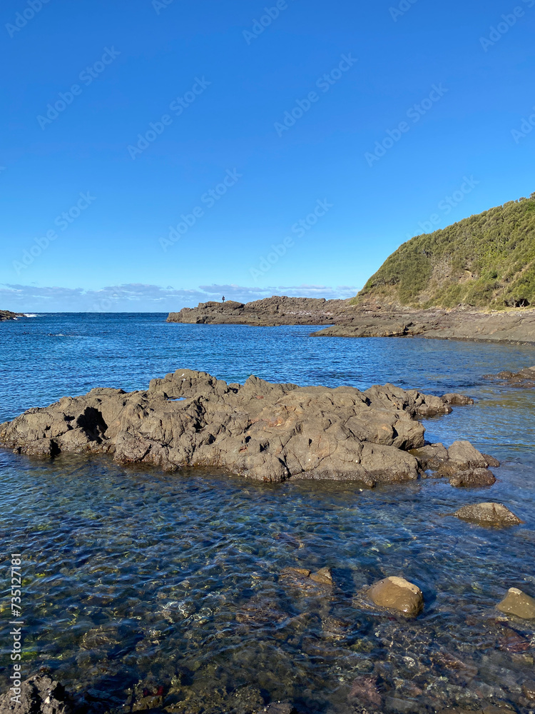 Island and rocky sea coast. View of ocean, mountains and shoreline. Landscape of a bay.