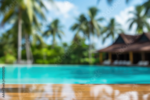 Tropical blurred background with empty table top near swimming pool on sunny day. Copy space.
