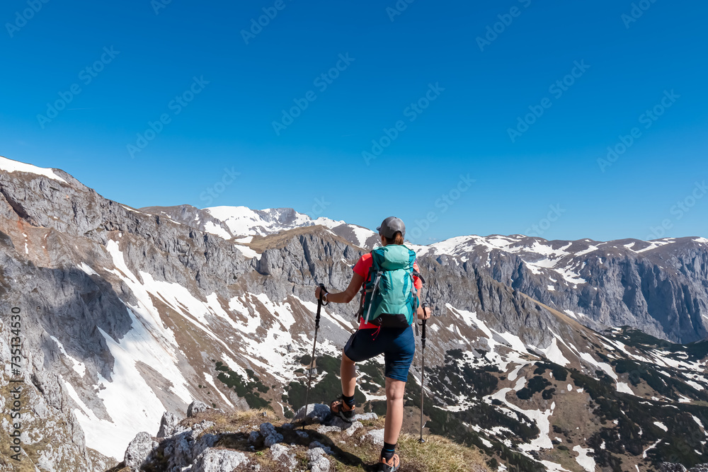Hiker woman with panoramic view of majestic mountain peak Ringkamp in wild Hochschwab massif, Styria, Austria. Scenic hiking trail in remote Austrian Alps on sunny day. Wanderlust in alpine spring