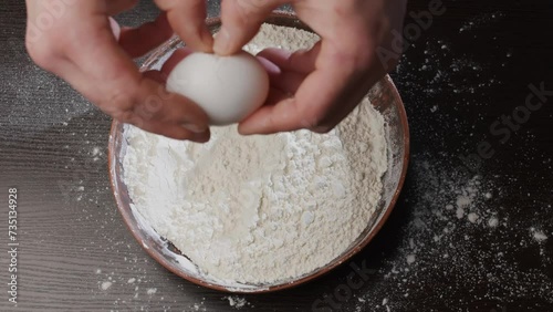 An egg falls into a plate with flour