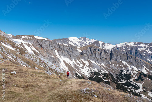 Hiker woman with panoramic view of majestic mountain peak Ringkamp in wild Hochschwab massif, Styria, Austria. Scenic hiking trail in remote Austrian Alps on sunny day. Wanderlust in alpine spring photo