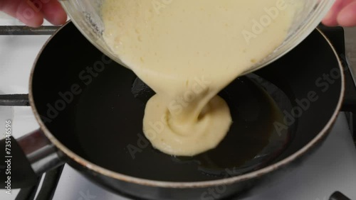 Pouring beaten eggs on hot frying pan with oil, close up