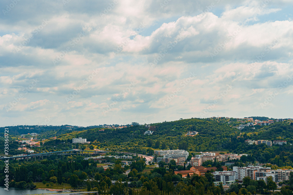 A view of Coimbra City under a clear sky, with trees and buildings. Landscape background and wallpaper.