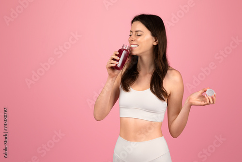 A health-conscious woman in white sportswear enjoys a fresh beetroot juice while holding a bottle cap