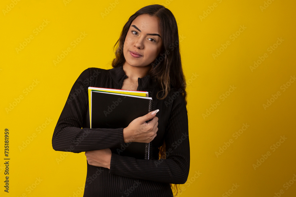 Sexy woman with long curly hair wearing a black textured outfit and holding books and notebooks Sexy woman with long curly hair wearing a black textured outfit and holding books and notebooks