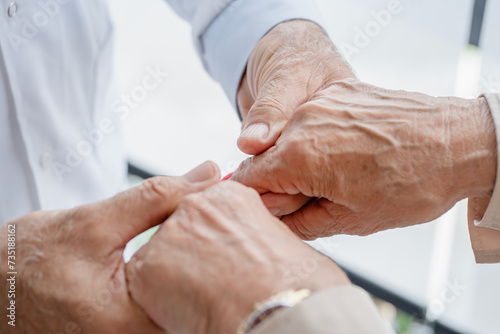 A close-up image of a doctor providing support by holding the hands of an elderly patient