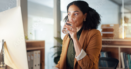 Woman at desk with computer, drinking water and typing email, report or article at digital agency. Internet, research and happy businesswoman at tech startup with glass, networking or project at work