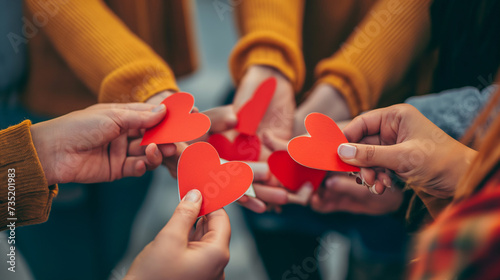 close de um grupo de jovens segurando corações de papel vermelho nas mãos