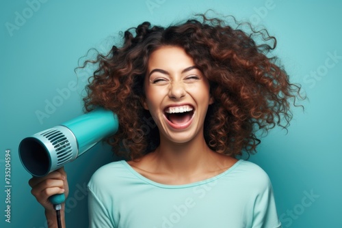 A woman with curly hair holding a blow dryer. Perfect for beauty and hairstyling related content photo