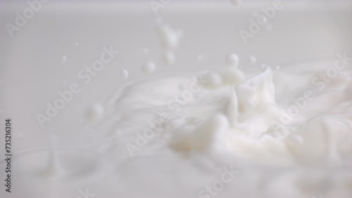 Fresh milk drop falling and splashing in a milky pool. Pouring milk in slow motion photo