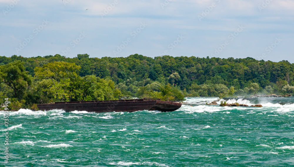 Old rusty iron barge stuck on rocks in a lake near Niagara Falls, Niagara State Park, USA