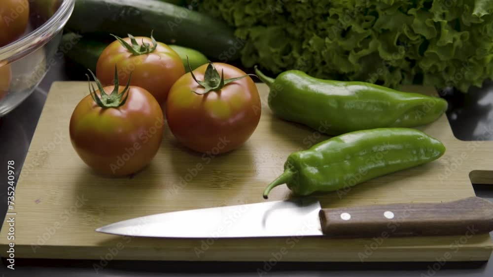 fresh vegetables to prepare a healthy salad, tomatoes, lettuce, green peppers, cucumbers, on a bamboo cutting board next to a knife fresh vegetables to prepare a healthy salad, tomatoes, lettuce, green peppers, cucumbers, on a bamboo cutting board next to a knife